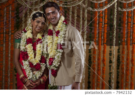 young bride and groom wearing garlands during traditional indian