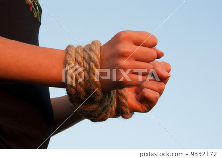 图库照片: hands tied up with rope against blue sky