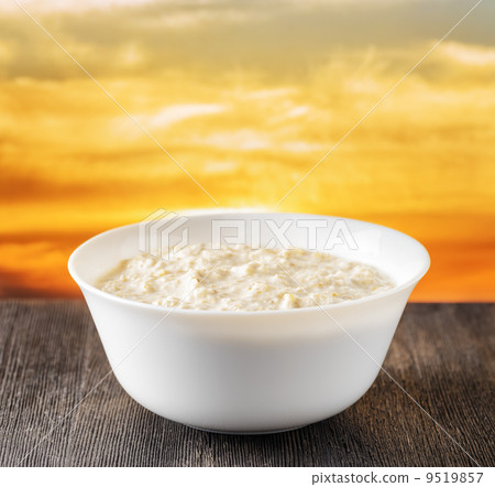 bowl of oat porridge on nature background - stock photo [9519857