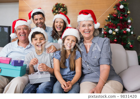 extended family in christmas hats with gift boxes in living room