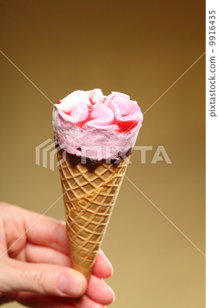 图库照片: berry icecream cone in hand on brown