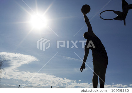 silhouette of a basketball player slam dunking the ball on a