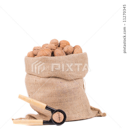 图库照片: full sack with walnuts and nutcracker.