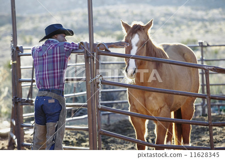 young man in a cowboy outfit petting a horse 11628345