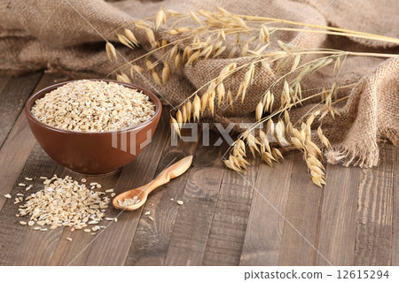 图库照片: oatmeal in a clay bowl, stalks of oats on the back