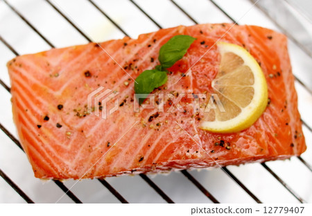 图库照片: marinated salmon fillet with lemon on grill