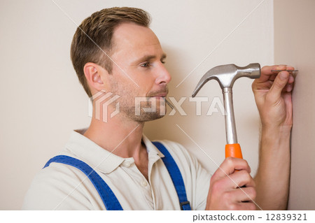 图库照片: man hammering nail in the wall