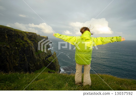 图库照片: a young woman with her arms raised by the cliff