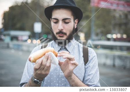 图库照片: young handsome hipster gay modern man eating hot dog