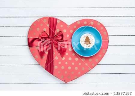 图库照片: gift box and cappuccino on white wooden table.
