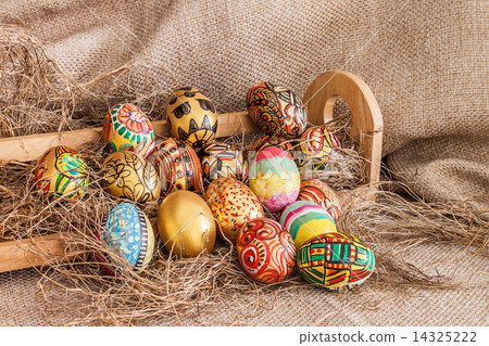 图库照片: colorful painted easter egg on hay in wooden shelf