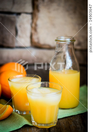 图库照片 glass of orange juice with ice and sliced oranges on