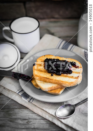 图库照片: toasted bread with jam and milk on wooden background