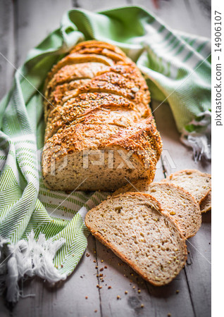 图库照片: sliced loaf of seeded bread on wooden background