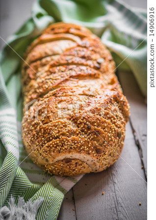 图库照片: sliced loaf of seeded bread on wooden background