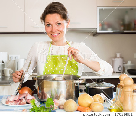 图库照片: young woman cooking soup with meat