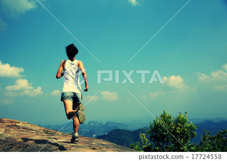 图库照片: young asian woman running on mountain peak cliff