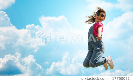 图库照片: happy little girl jumping high over blue sky