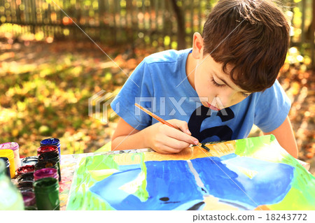 图库照片: boy paint a picture on the autumn background