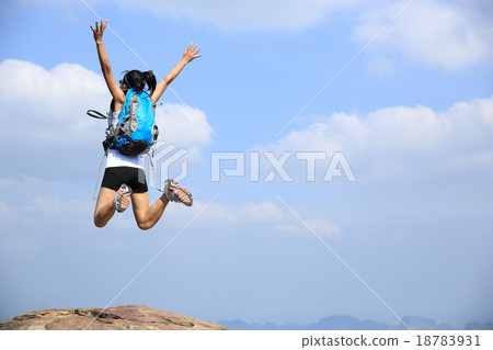 图库照片: young asian woman jumping on mountain peak cliff