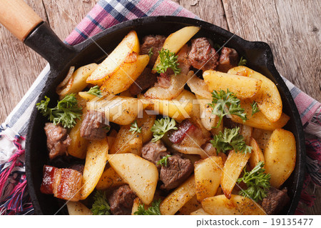 图库照片: fried potatoes with meat and bacon in pan close-up