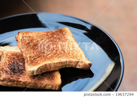 图库照片: slice toasted bread on black dish.