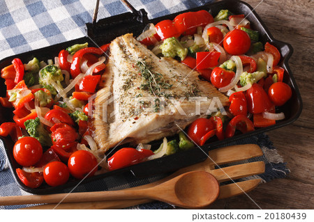 图库照片: flatfish with vegetables close-up on a frying pan