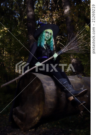 young girl with green hair and broom in suit of witch in forest