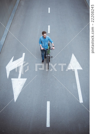图库照片: pleasant guy walking along the road with bicycle
