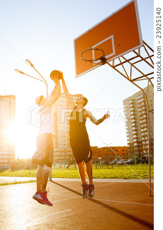 Play basketball,read a book 图库照片: two guy play basketball at district sports ground.