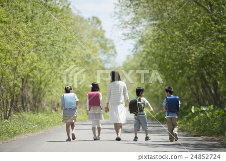 图库照片: 小学生走在一条路和老师的背上