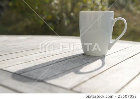 图库照片: drinking cup on a wooden table in the sun.