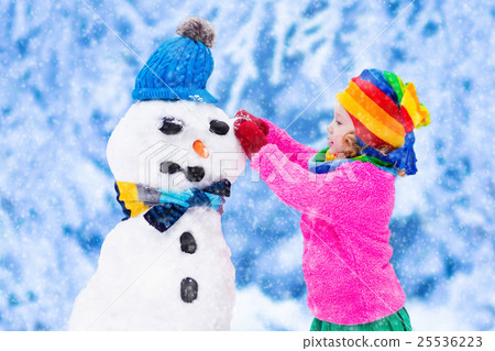 图库照片: little girl building a snow man in winter