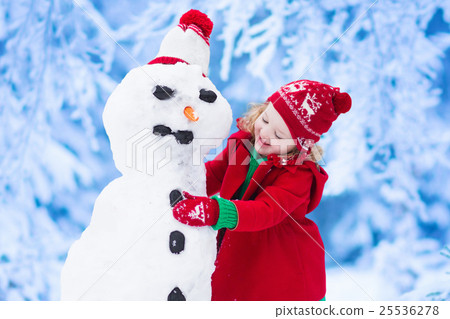 图库照片: little girl building a snow man in winter