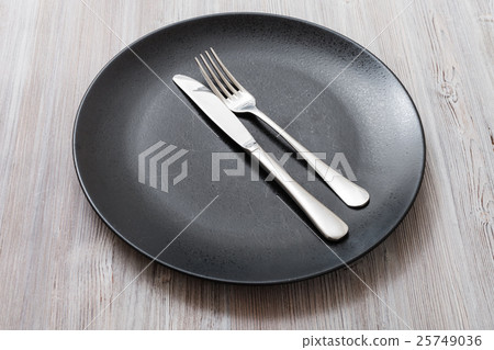 图库照片: black plate with parallel knife, spoon on gray