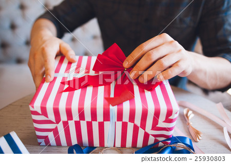 图库照片: man decorating gift box with red bow