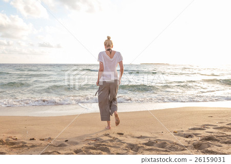 图库照片: woman walking on sand beach at golden hour