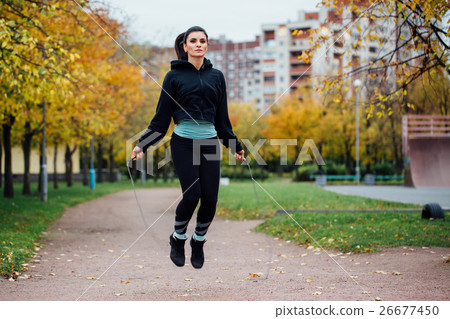 图库照片: woman feet jumping, using skipping rope in park.