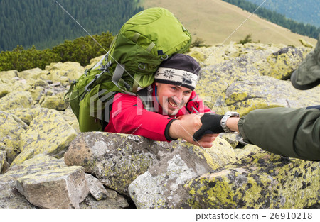 图库照片: hand helping hiker to climb the mountain