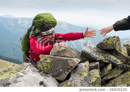 图库照片: hand helping hiker to climb the mountain