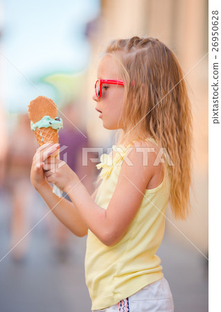 图库照片: adorable little girl eating ice-cream outdoors at