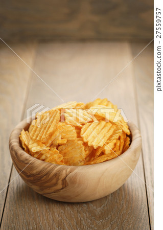 图库照片: rippled potato chips with paprika in wooden bowl