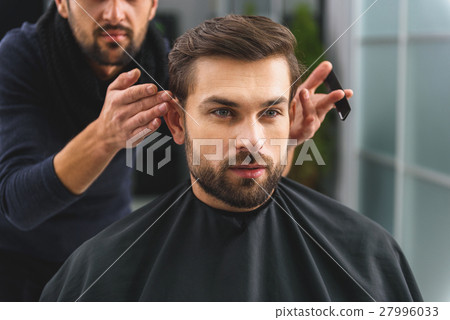 图库照片: handsome guy getting haircut at salon