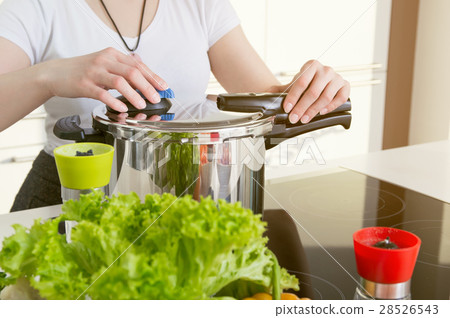 图库照片: woman uses pressure cooker to cook a meal.