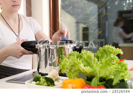 图库照片: woman uses pressure cooker to cook a meal.