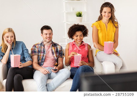 图库照片 happy friends with popcorn watching tv at home