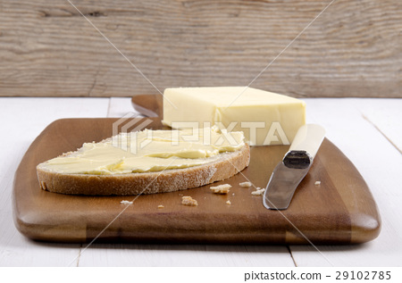 图库照片: slice of bread on a wooden board with butter