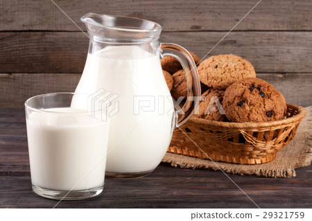 图库照片: jug and glass of milk with oatmeal cookies in a