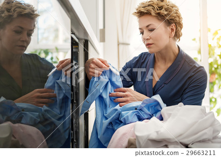 图库照片: serious housewife looking at dirty clothes