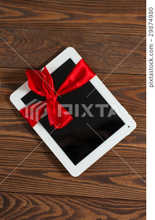 照片素材(图片): tablet with red bow, a gift wooden background